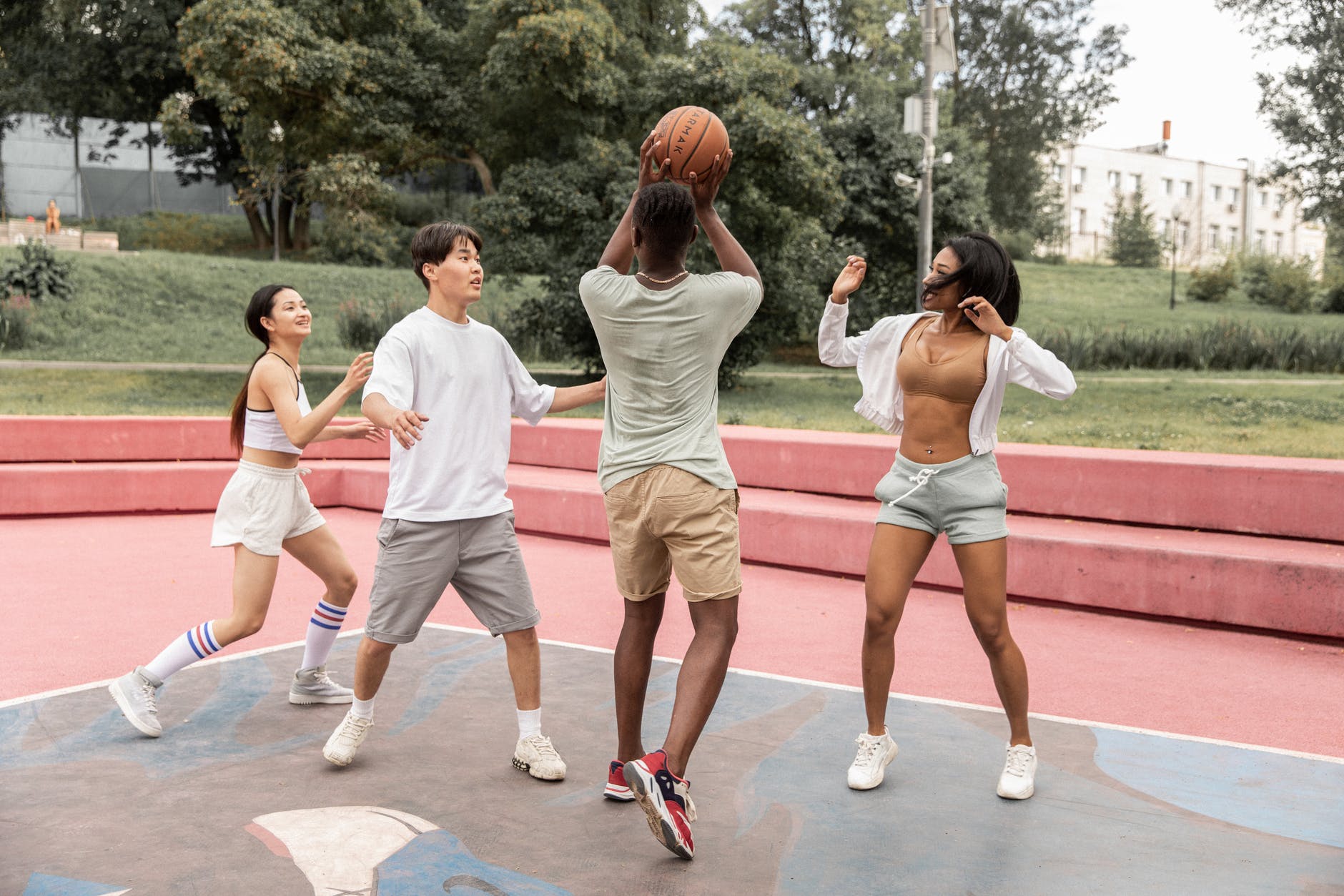 young multiethnic sportspeople playing basketball on court in park